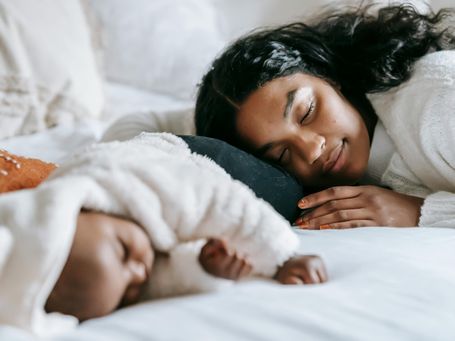 Mutter entspannt mit schlafendem Baby – Hilfe im Wochenbett sorgt für Ruhe