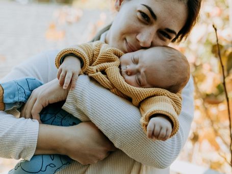 Neugeborenes schlafend im Arm der Mama – liebevolle Versorgung in der Wochenbettzeit