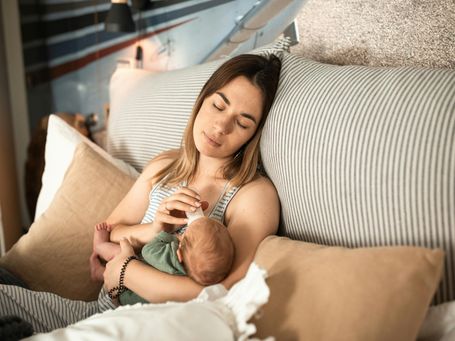 Mutter gibt Baby das Fläschchen – Unterstützung im Alltag durch haushaltsnahe Dienstleistungen
