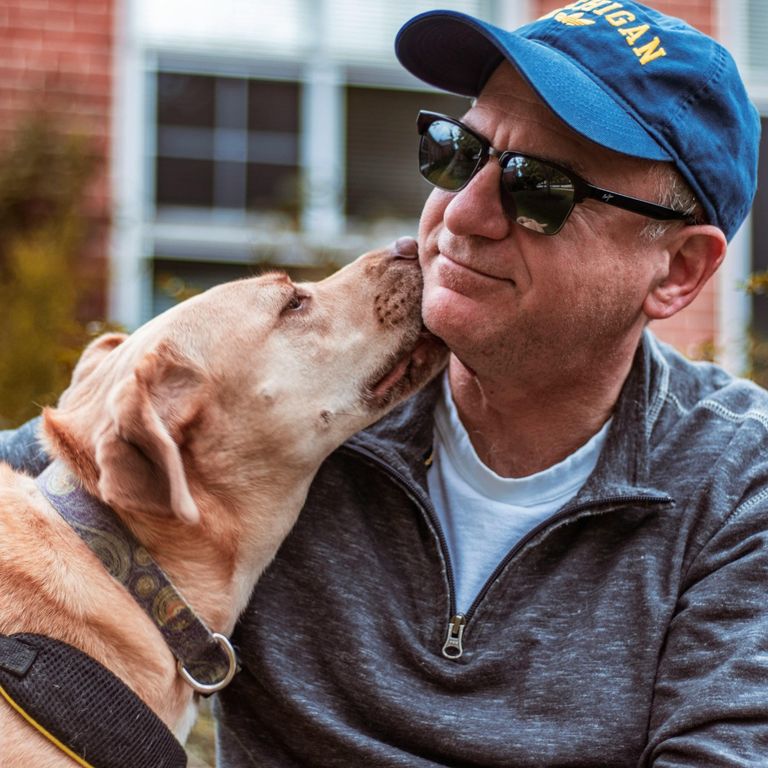 Mann bekommt Kuss von seinem Hund - wir unterstützen Sie beim Gassigehen wenn sie einmal verhindert sind